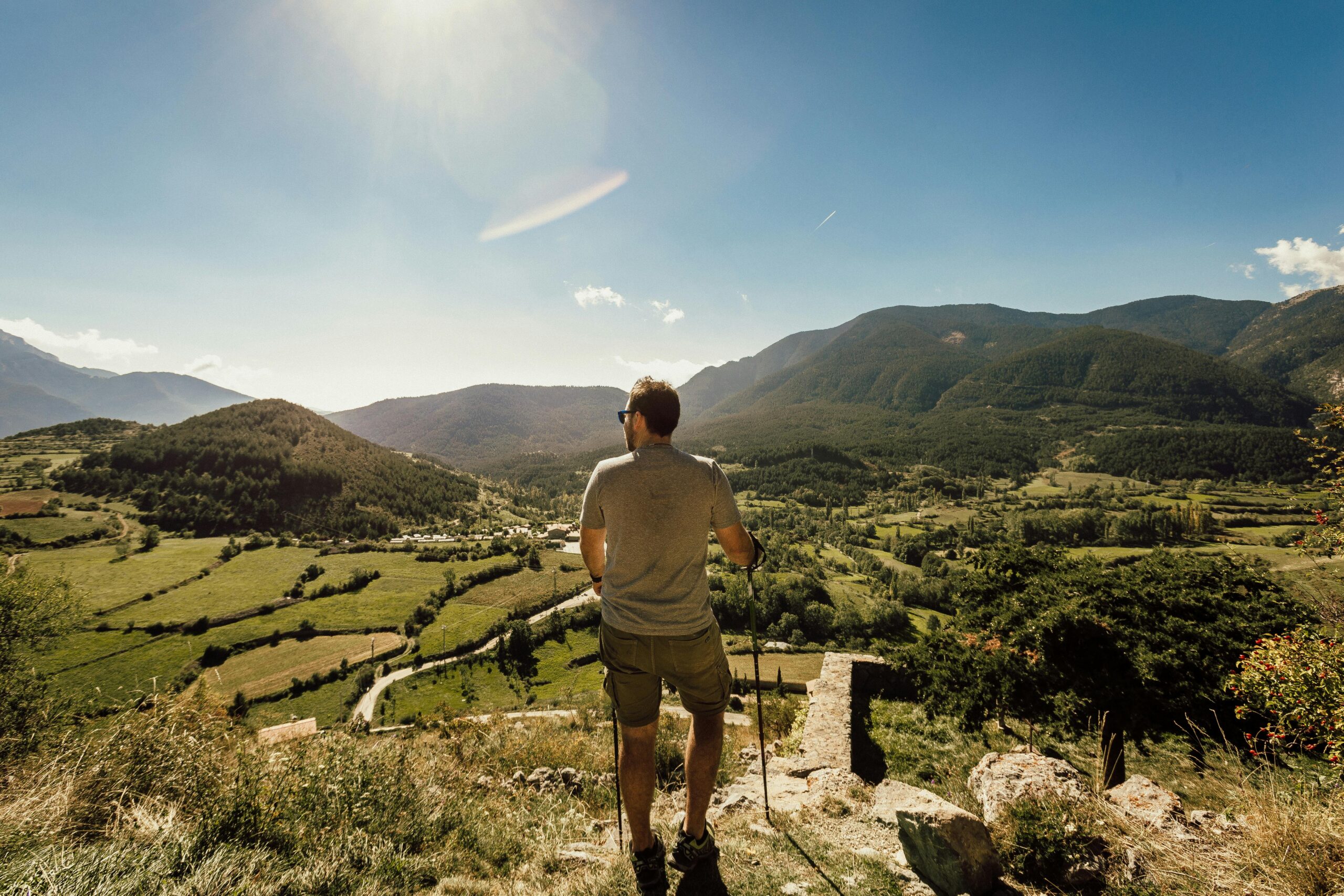 Man hiking in lush green mountains on a bright summer day.